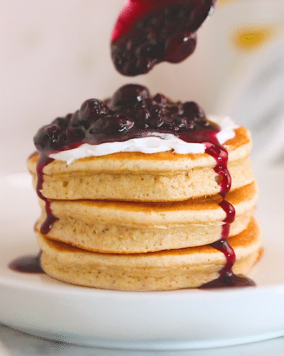 Drizzling berries over a stack of Flourish x Yoggu pancakes